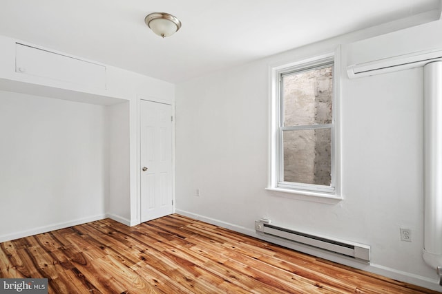 3545 Emerald St, Philadelphia, PA 19134 - unfurnished bedroom featuring baseboard heating, a wall mounted AC, wood finished floors, and baseboards
