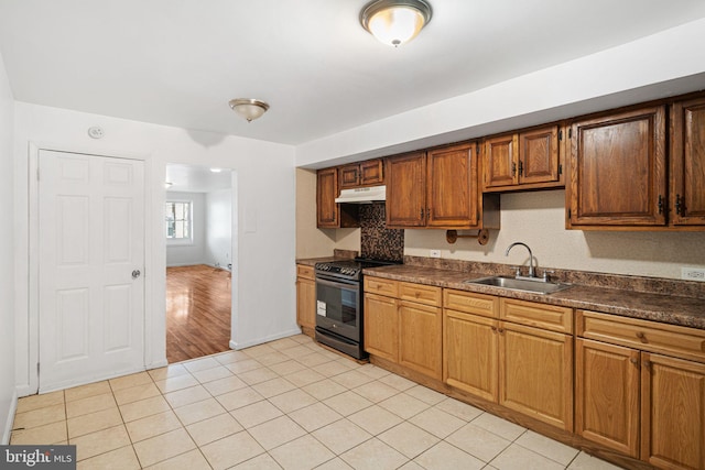 3545 Emerald St, Philadelphia, PA 19134 - kitchen featuring black range with electric cooktop, under cabinet range hood, a sink, dark countertops, and light tile patterned floors