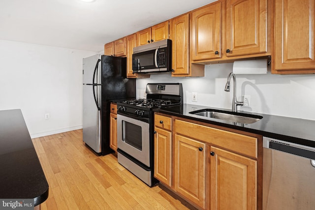 810 N Hancock St Unit 2, Philadelphia, PA 19123 - kitchen with stainless steel appliances, light wood-style flooring, dark countertops, and brown cabinetry