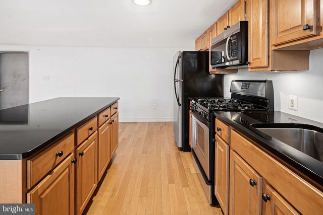 810 N Hancock St Unit 2, Philadelphia, PA 19123 - kitchen featuring gas stove, dark countertops, light wood-type flooring, and brown cabinets