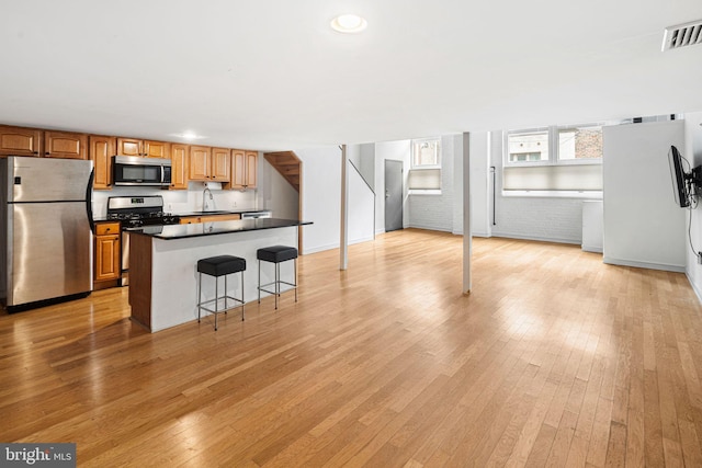 810 N Hancock St Unit 2, Philadelphia, PA 19123 - kitchen with appliances with stainless steel finishes, light wood-type flooring, a kitchen breakfast bar, a kitchen island, and brick wall