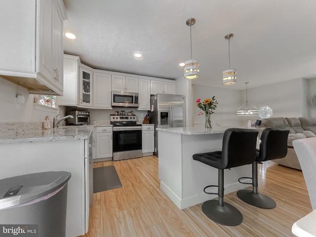 26055 Prospect Hill Rd, Mechanicsville, MD 20659 - kitchen featuring appliances with stainless steel finishes, light wood-style flooring, white cabinets, glass insert cabinets, and recessed lighting