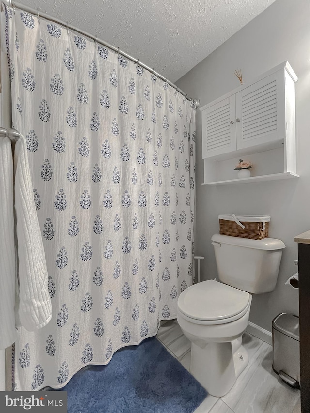 26055 Prospect Hill Rd, Mechanicsville, MD 20659 - bathroom with toilet, a textured ceiling, a shower with shower curtain, and baseboards