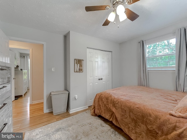 26055 Prospect Hill Rd, Mechanicsville, MD 20659 - bedroom with light wood-style floors, a closet, a ceiling fan, a textured ceiling, and baseboards