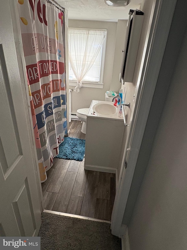 632 Bath Rd, Bristol, PA 19007 - bathroom featuring vanity, toilet, wood finished floors, baseboard heating, and a shower with curtain