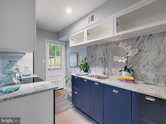 5019 Just St NE, Washington, DC 20019 - kitchen with blue cabinets, a sink, backsplash, light stone countertops, and light wood-style flooring
