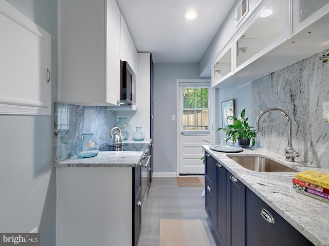 5019 Just St NE, Washington, DC 20019 - kitchen with blue cabinetry, a sink, stainless steel microwave, backsplash, and white cabinetry