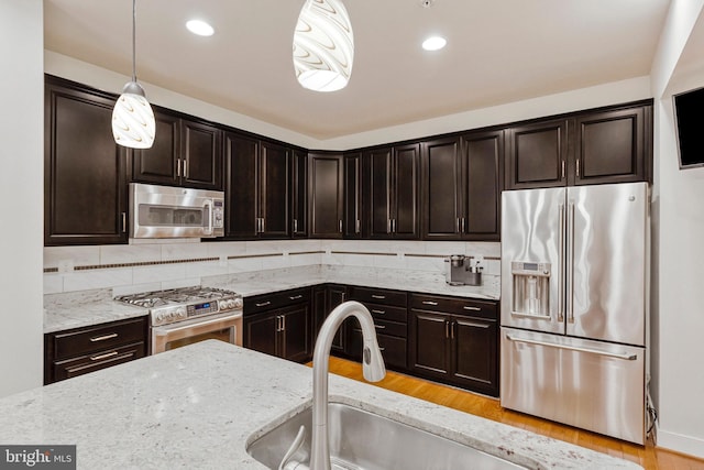 9726 Knowledge Dr, Laurel, MD 20723 - kitchen with stainless steel appliances, light stone countertops, pendant lighting, decorative backsplash, and dark brown cabinets