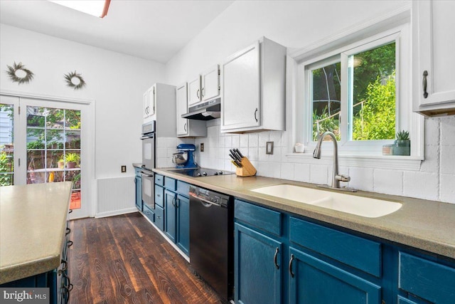 413 E A St, Brunswick, MD 21716 - kitchen with blue cabinetry, black appliances, under cabinet range hood, dark wood finished floors, and a wainscoted wall