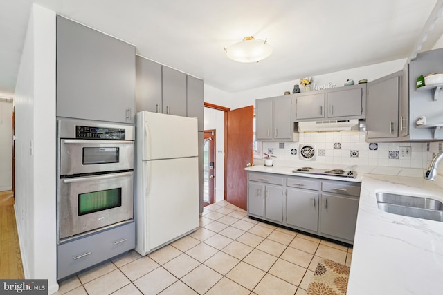 1323 Dorchester Ave, Gwynn Oak, MD 21207 - kitchen featuring white appliances, gray cabinetry, a sink, under cabinet range hood, and backsplash