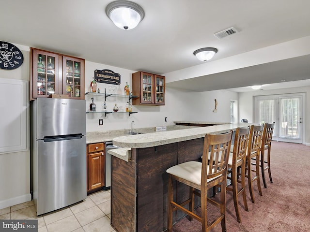 15446 Symondsbury Way, Upper Marlboro, MD 20774 - kitchen with freestanding refrigerator, a breakfast bar area, glass insert cabinets, light tile patterned flooring, and a sink