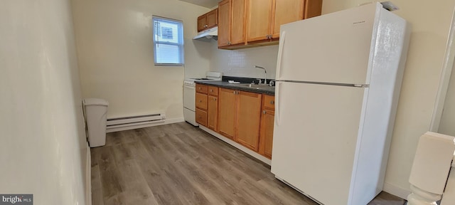 3063 Joyce St, Philadelphia, PA 19134 - kitchen featuring white appliances, a baseboard heating unit, a sink, dark countertops, and under cabinet range hood