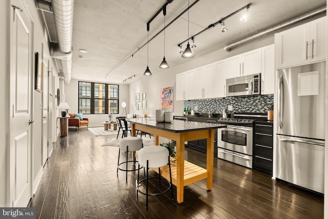 2125 14th St NW Unit 427, Washington, DC 20009 - kitchen featuring appliances with stainless steel finishes, dark wood-style floors, white cabinets, and backsplash