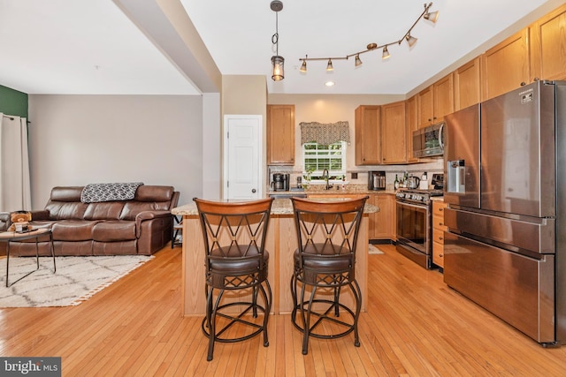 6529 Carston Ct, Frederick, MD 21703 - kitchen with appliances with stainless steel finishes, light wood finished floors, a center island, light countertops, and a kitchen breakfast bar