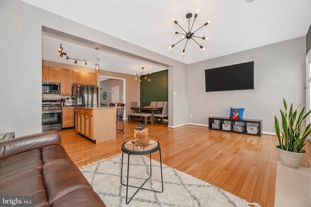 6529 Carston Ct, Frederick, MD 21703 - living room featuring a chandelier, light wood-style floors, and baseboards