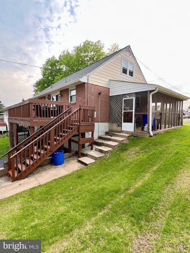 838 N Hanover St, Pottstown, PA 19464 - rear view of property featuring a sunroom, a lawn, brick siding, a deck, and stairway