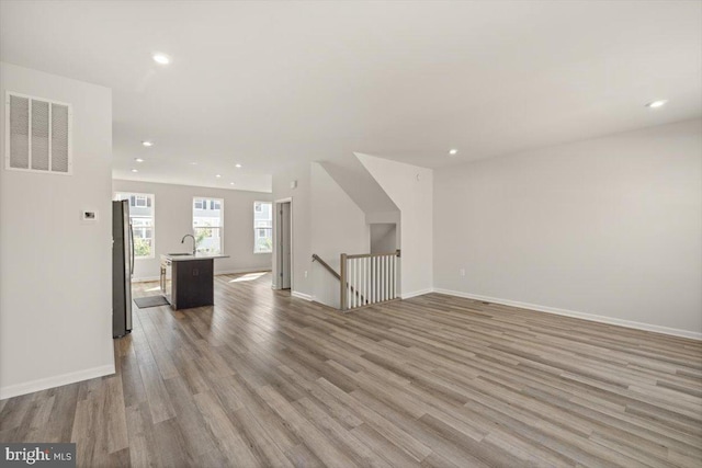 64 Anthem St, Ranson, WV 25438 - unfurnished living room with light wood-type flooring, recessed lighting, baseboards, and a sink