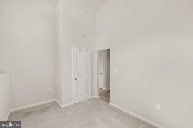 64 Anthem St, Ranson, WV 25438 - empty room featuring light colored carpet, baseboards, high vaulted ceiling, and a smoke detector