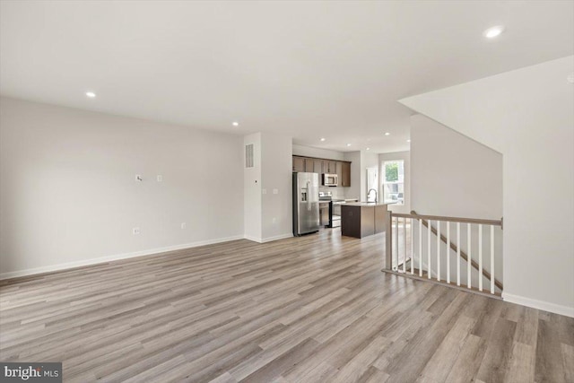 64 Anthem St, Ranson, WV 25438 - unfurnished living room with light wood-style flooring, recessed lighting, a sink, and baseboards