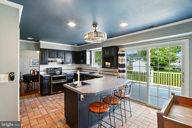 6082 Drum Point Rd, Deale, MD 20751 - kitchen with double oven range, brick patterned flooring, a breakfast bar area, under cabinet range hood, and crown molding