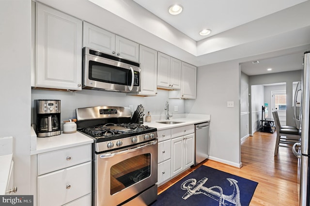 104 S St, Annapolis, MD 21401 - kitchen featuring appliances with stainless steel finishes, a sink, light wood-type flooring, white cabinetry, and baseboards