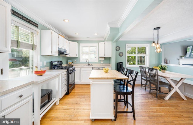 1323 Washington Dr, Annapolis, MD 21403 - kitchen featuring black appliances, crown molding, under cabinet range hood, a kitchen bar, and white cabinetry