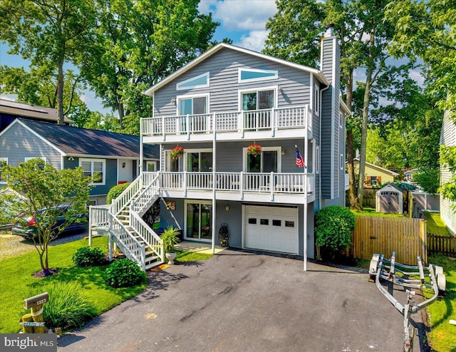 1323 Washington Dr, Annapolis, MD 21403 - view of front facade with asphalt driveway, a garage, a chimney, a balcony, and stairs