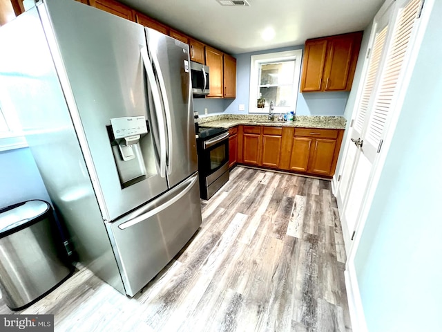10213 Duvawn Pl, Silver Spring, MD 20902 - kitchen featuring stainless steel appliances, light wood-type flooring, brown cabinets, and light stone counters