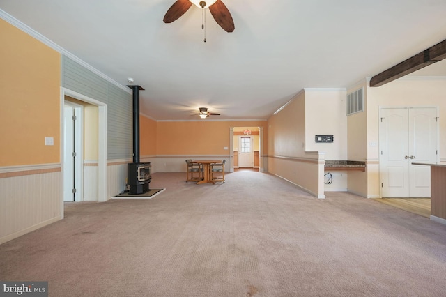 44 Homberg Cir, Dover, DE 19904 - unfurnished living room with a ceiling fan, a wood stove, ornamental molding, carpet, and wainscoting