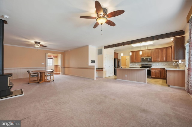 44 Homberg Cir, Dover, DE 19904 - unfurnished living room featuring a wood stove, ceiling fan, a sink, light colored carpet, and a wainscoted wall