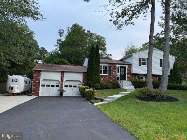 1247 Silver Run Dr, Pasadena, MD 21122 - split level home featuring a detached garage, a front lawn, and brick siding