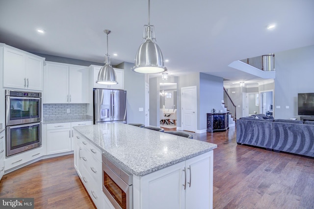 41031 Brook Grove Dr, Aldie, VA 20105 - kitchen with appliances with stainless steel finishes, open floor plan, decorative backsplash, wood finished floors, and a center island