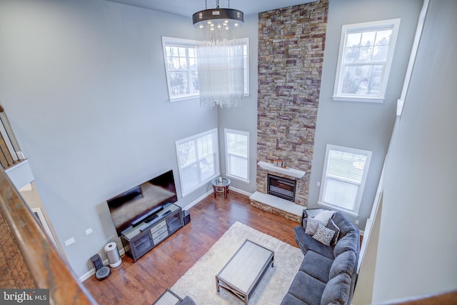 41031 Brook Grove Dr, Aldie, VA 20105 - living room featuring a chandelier, wood finished floors, a stone fireplace, a towering ceiling, and baseboards
