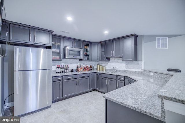 41031 Brook Grove Dr, Aldie, VA 20105 - kitchen featuring stainless steel appliances, a sink, light stone countertops, glass insert cabinets, and a peninsula