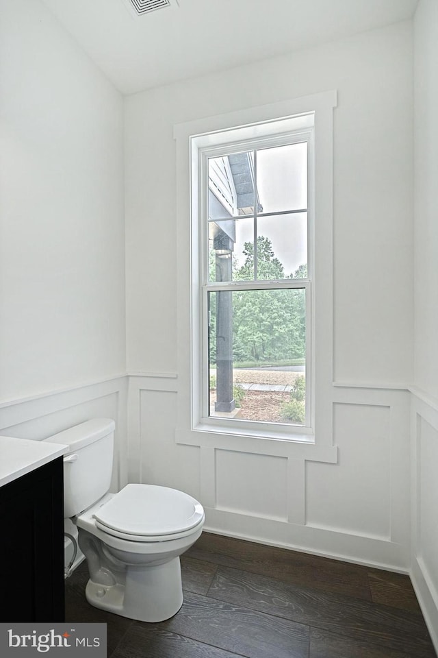 2741 Primrose Ln N, York, PA 17404 - half bath featuring a decorative wall, toilet, vanity, a wainscoted wall, and wood finished floors