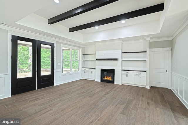 2741 Primrose Ln N, York, PA 17404 - unfurnished living room with a decorative wall, wood finished floors, a glass covered fireplace, beam ceiling, and a wainscoted wall