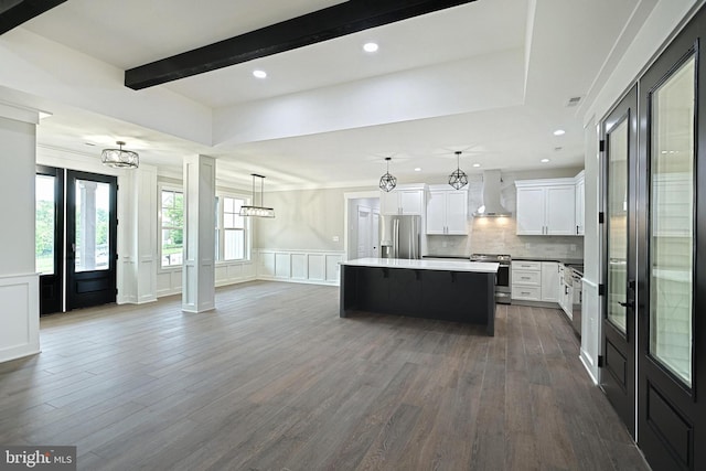 2741 Primrose Ln N, York, PA 17404 - kitchen with wall chimney exhaust hood, appliances with stainless steel finishes, a decorative wall, a kitchen island, and white cabinetry