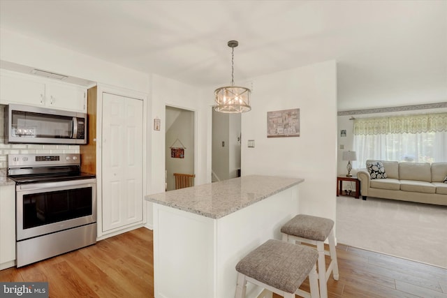 143 Brittany Dr, Chalfont, PA 18914 - kitchen with stainless steel appliances, a breakfast bar, a chandelier, white cabinets, and light wood-type flooring