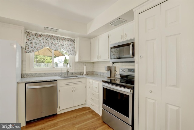 143 Brittany Dr, Chalfont, PA 18914 - kitchen with appliances with stainless steel finishes, decorative backsplash, white cabinetry, and light wood-type flooring