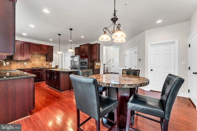 3913 Rolling Paddock Dr, Upper Marlboro, MD 20772 - kitchen featuring appliances with stainless steel finishes, a center island, a sink, dark wood-type flooring, and tasteful backsplash