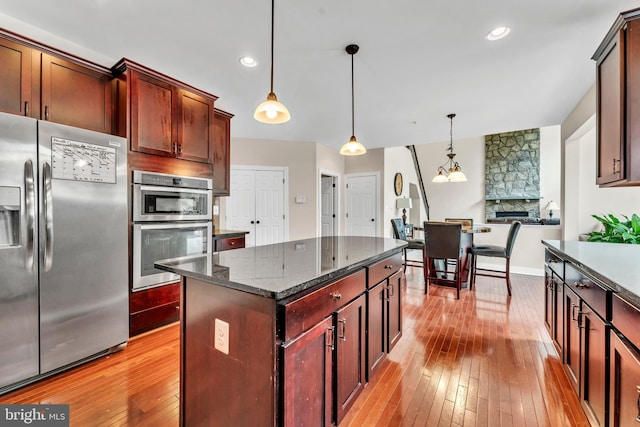 3913 Rolling Paddock Dr, Upper Marlboro, MD 20772 - kitchen with stainless steel appliances, light wood-style flooring, pendant lighting, dark stone countertops, and a kitchen island