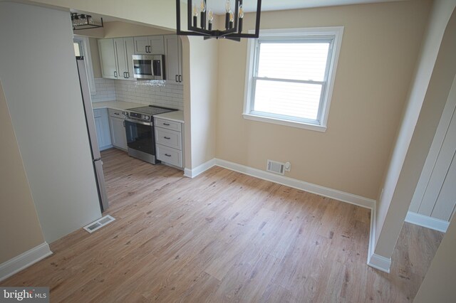 180 Carroll Rd, Pasadena, MD 21122 - kitchen featuring appliances with stainless steel finishes, light wood-type flooring, light countertops, tasteful backsplash, and a chandelier