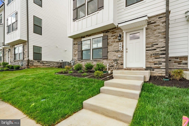 7417 Calm Retreat Blvd, Brandywine, MD 20613 - doorway to property featuring stone siding, board and batten siding, a lawn, and central air condition unit