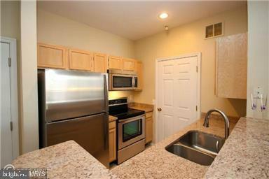 1581 Spring Gate Dr Unit 5207, Mclean, VA 22102 - kitchen with stainless steel appliances, light brown cabinetry, a sink, recessed lighting, and light stone counters