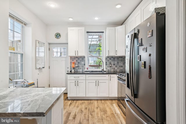1523 N Hollywood St, Philadelphia, PA 19121 - kitchen featuring stainless steel appliances, light wood finished floors, white cabinetry, a sink, and tasteful backsplash