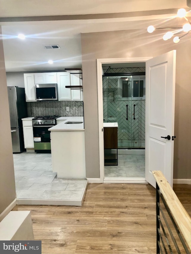 300 Darcy Ave, Hamilton, NJ 08629 - kitchen featuring appliances with stainless steel finishes, white cabinetry, baseboards, light wood-type flooring, and a sink
