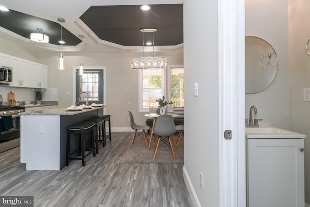 2817 Waldorf Ave, Baltimore, MD 21215 - kitchen featuring stainless steel appliances, crown molding, wood finished floors, a kitchen breakfast bar, and baseboards