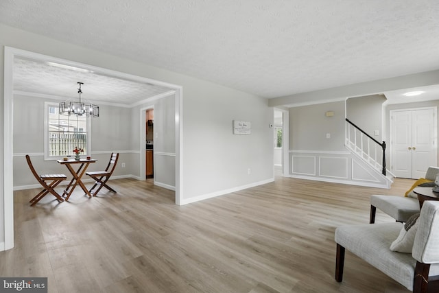 14612 Orangewood St, Silver Spring, MD 20905 - living room with stairway, light wood-style floors, a chandelier, a textured ceiling, and crown molding