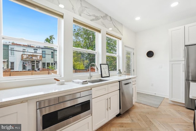 1351 Newton St NW, Washington, DC 20010 - kitchen with appliances with stainless steel finishes, a sink, recessed lighting, white cabinets, and light stone counters