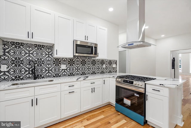 1630 E Biddle St, Baltimore, MD 21213 - kitchen featuring appliances with stainless steel finishes, island range hood, a peninsula, light wood-type flooring, and recessed lighting
